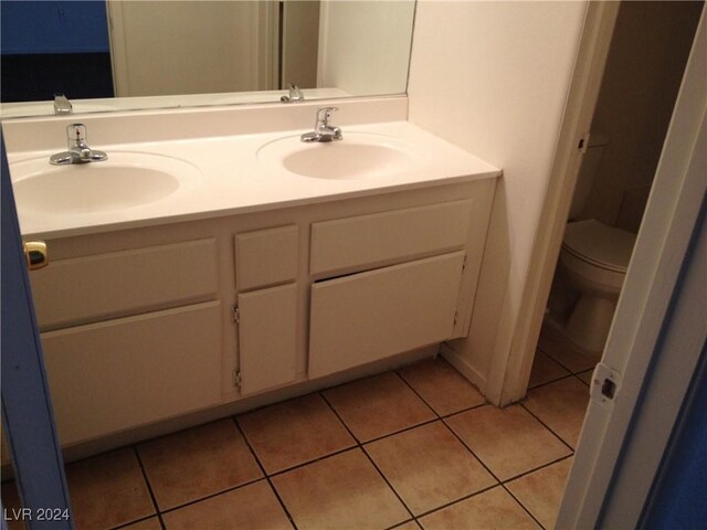 bathroom featuring toilet, dual bowl vanity, and tile patterned flooring