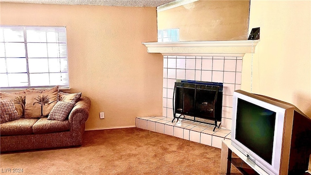 living room with a tile fireplace, carpet flooring, and a textured ceiling