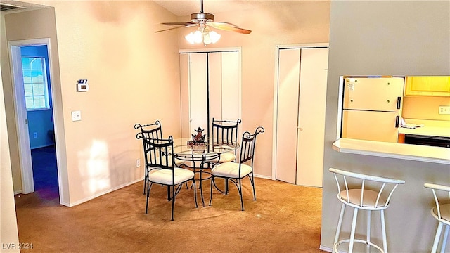 carpeted dining area with ceiling fan