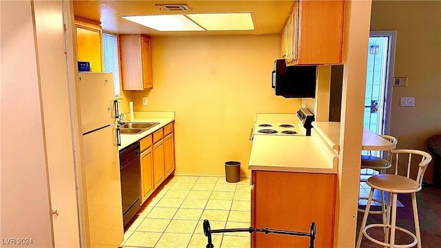 kitchen featuring range with electric cooktop, light tile patterned flooring, dishwasher, a kitchen breakfast bar, and fridge