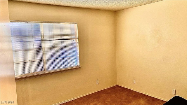 empty room featuring dark colored carpet and a textured ceiling