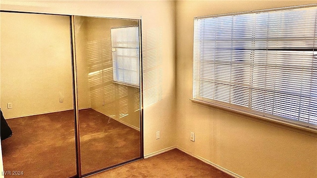 unfurnished bedroom with multiple windows, a closet, and carpet flooring