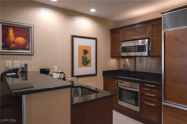 kitchen featuring appliances with stainless steel finishes, sink, kitchen peninsula, light tile patterned floors, and dark brown cabinets