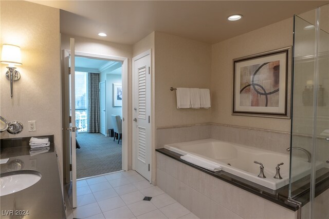 bathroom with tiled bath, vanity, and tile patterned floors