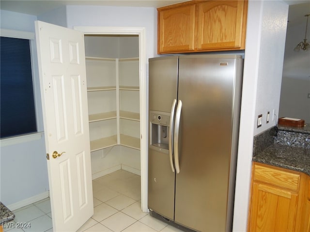 interior space with dark stone countertops, stainless steel fridge with ice dispenser, and light tile patterned flooring