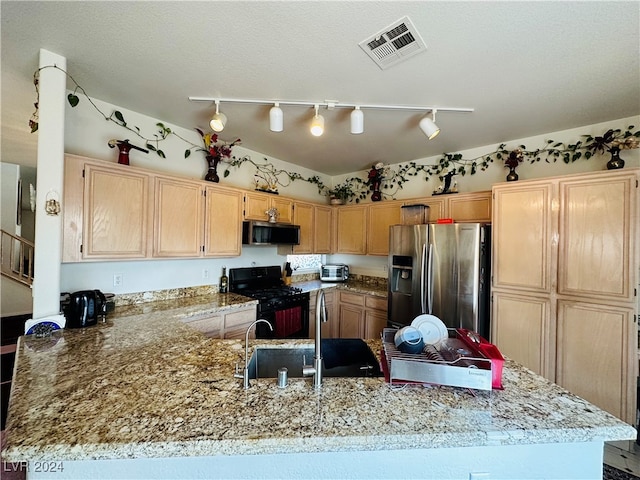 kitchen with appliances with stainless steel finishes, rail lighting, kitchen peninsula, and light brown cabinetry