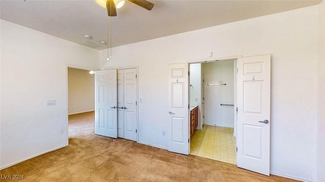 unfurnished bedroom featuring ceiling fan, ensuite bathroom, a closet, and light carpet