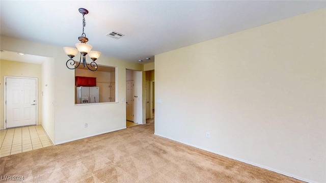 spare room with light carpet and an inviting chandelier