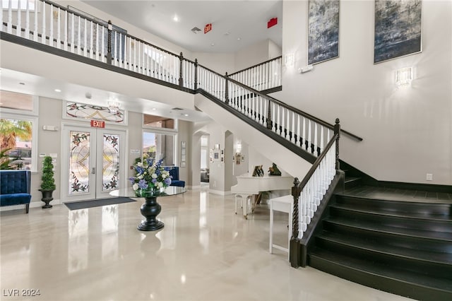 stairway featuring a towering ceiling, french doors, and concrete floors