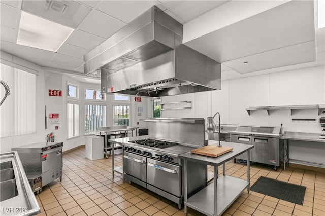 kitchen featuring light tile patterned flooring, white cabinets, stainless steel counters, and exhaust hood