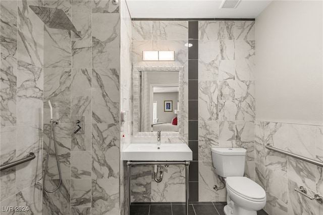 bathroom with tiled shower, tile walls, vanity, tile patterned flooring, and toilet