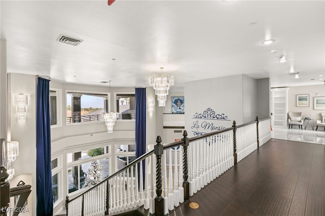 hallway with wood-type flooring and a notable chandelier