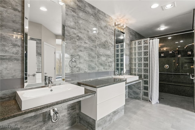 bathroom featuring tile walls, double sink vanity, tile patterned floors, and tiled shower