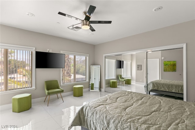 bedroom with light tile patterned floors, ceiling fan, and a closet