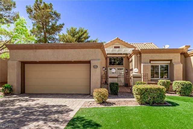 southwest-style home with stucco siding, a tile roof, decorative driveway, a front yard, and a garage