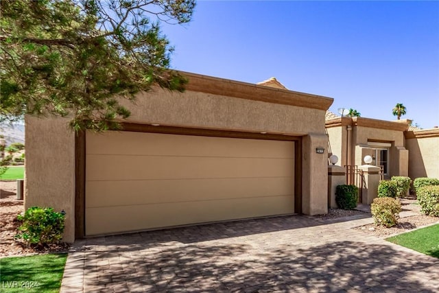 southwest-style home featuring stucco siding, decorative driveway, and an attached garage