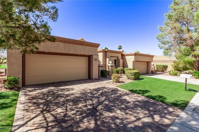 pueblo-style home featuring stucco siding, an attached garage, and a front lawn