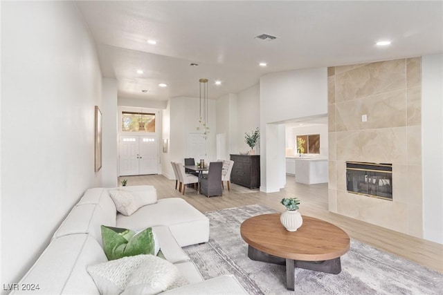 living room with recessed lighting, visible vents, a tiled fireplace, and light wood finished floors