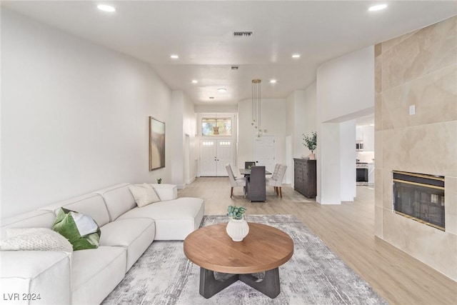 living room with a tiled fireplace, visible vents, recessed lighting, and light wood-style floors