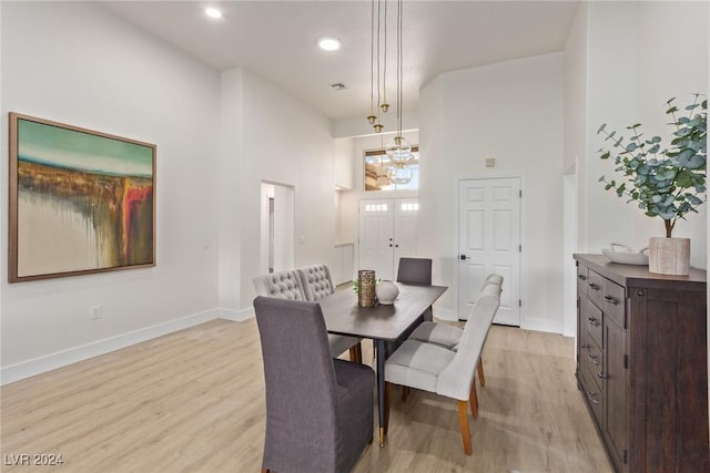 dining room with light wood finished floors, recessed lighting, baseboards, and a towering ceiling