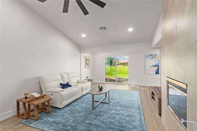 living area with light wood finished floors, visible vents, a fireplace, and baseboards