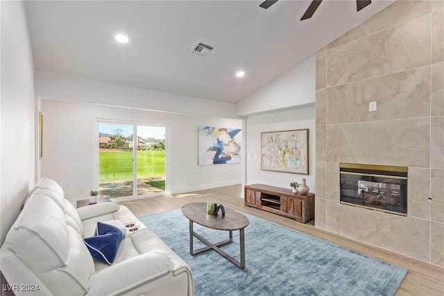 living area with wood finished floors, visible vents, recessed lighting, vaulted ceiling, and a tiled fireplace