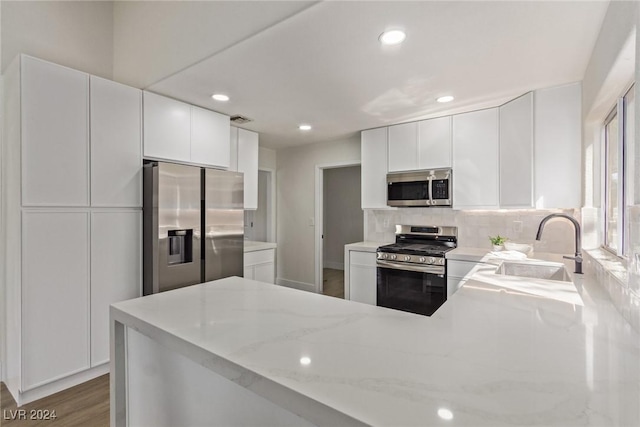 kitchen with light stone counters, wood finished floors, visible vents, a sink, and appliances with stainless steel finishes