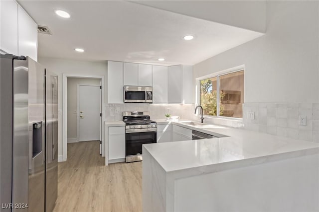 kitchen featuring visible vents, a peninsula, a sink, light countertops, and appliances with stainless steel finishes