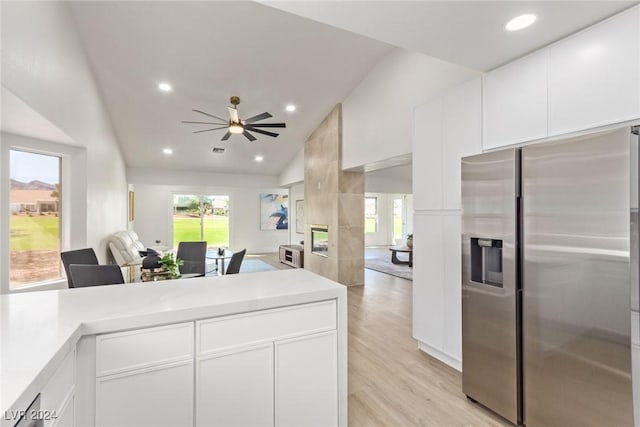 kitchen with open floor plan, light countertops, light wood-style floors, stainless steel refrigerator with ice dispenser, and white cabinets