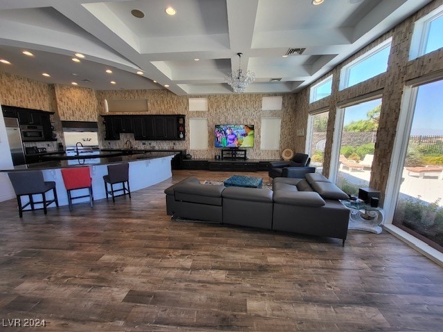 living room featuring sink, dark hardwood / wood-style flooring, coffered ceiling, beam ceiling, and a chandelier