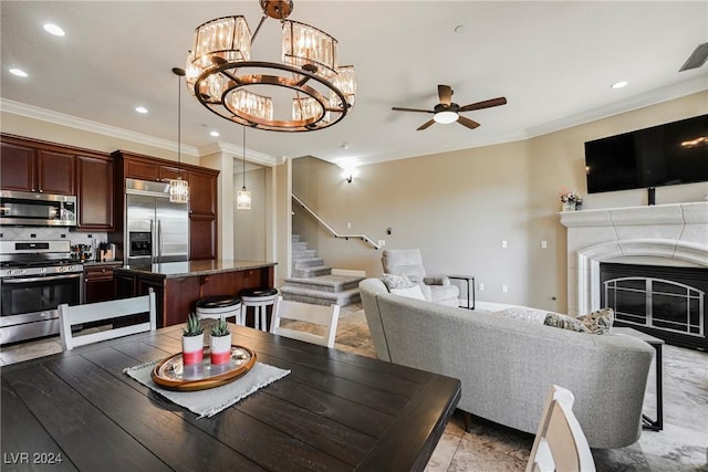 dining area with a glass covered fireplace, ceiling fan, stairway, ornamental molding, and recessed lighting