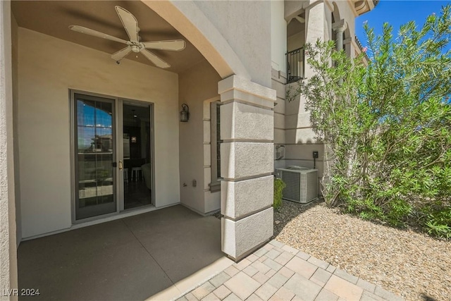 doorway to property with a patio area, ceiling fan, cooling unit, and stucco siding