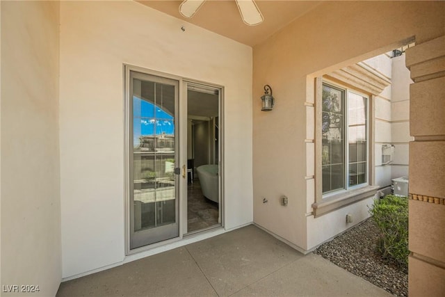 view of exterior entry with ceiling fan, a patio, and stucco siding