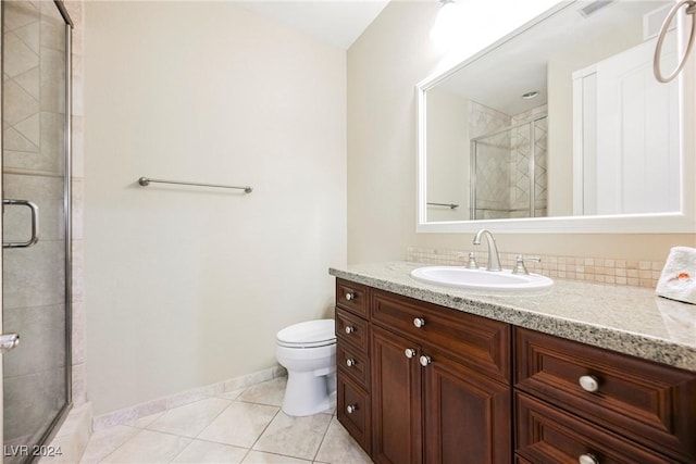 bathroom with tile patterned flooring, toilet, vanity, baseboards, and a shower stall