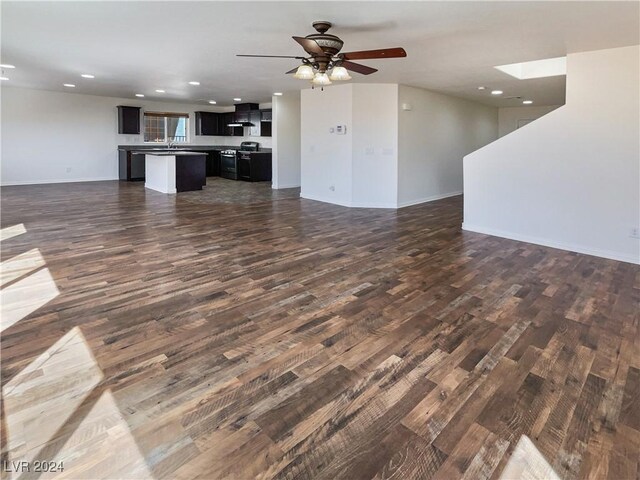 unfurnished living room with sink, ceiling fan, a skylight, and hardwood / wood-style flooring