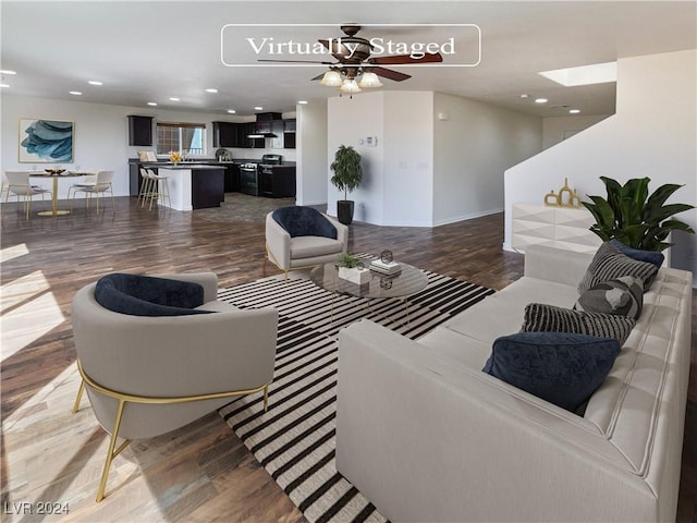 living room with ceiling fan, dark hardwood / wood-style floors, and a skylight