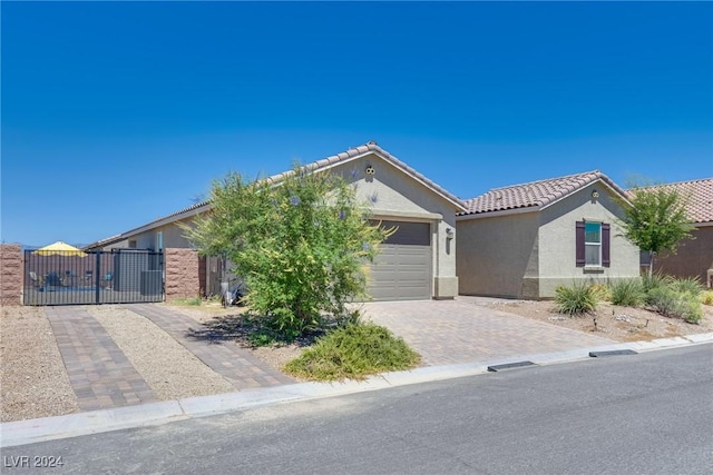 view of front of property featuring a garage, a tile roof, fence, decorative driveway, and stucco siding