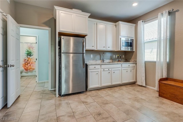 kitchen featuring white cabinetry, stainless steel appliances, and light stone counters