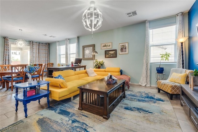 living area with light tile patterned floors, visible vents, and an inviting chandelier