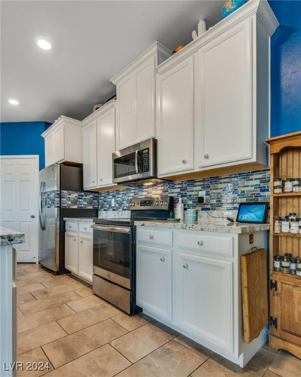 kitchen featuring stainless steel appliances, white cabinetry, and decorative backsplash