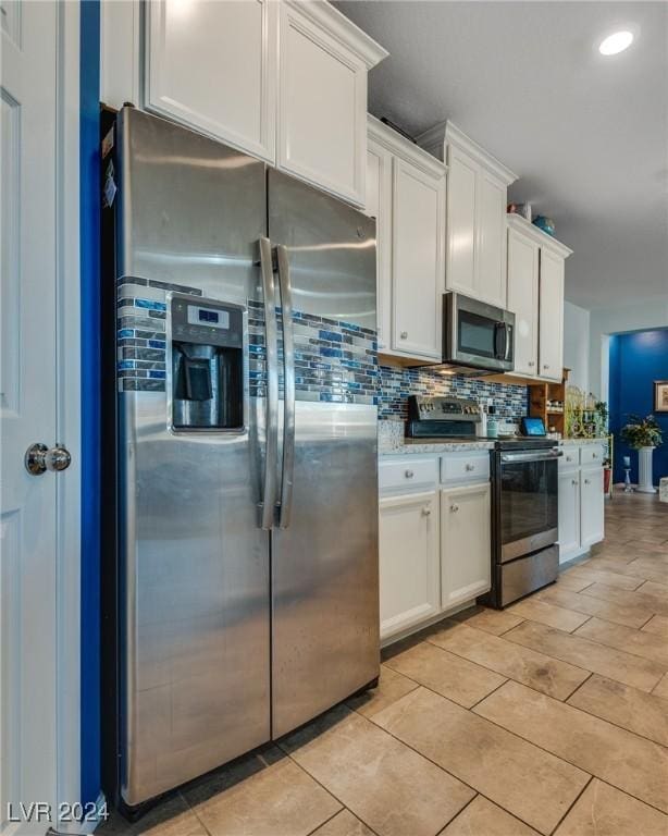 kitchen featuring stainless steel appliances, tasteful backsplash, light stone counters, and white cabinets