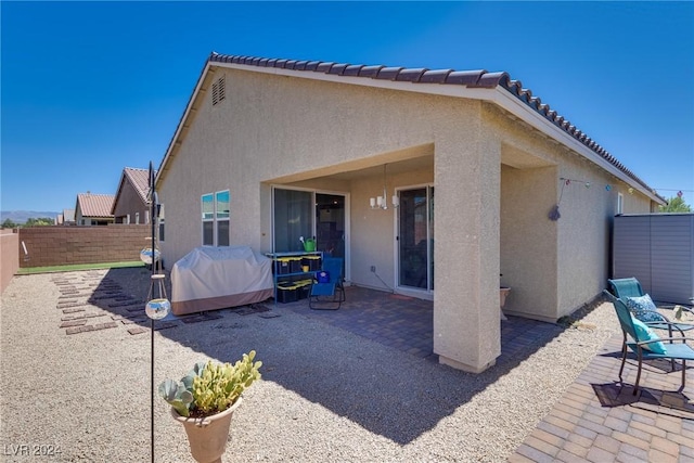 back of house featuring a tiled roof, a patio, fence, and stucco siding