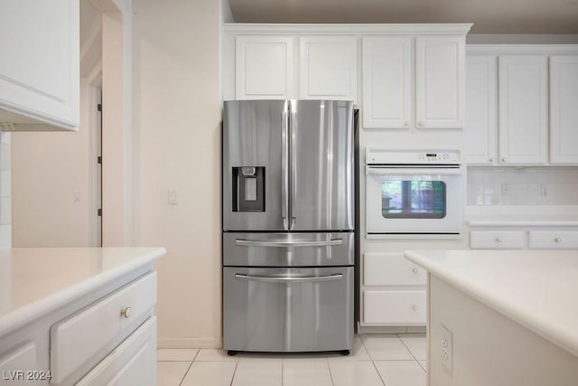 kitchen featuring light tile patterned floors, white cabinets, white oven, light countertops, and stainless steel refrigerator with ice dispenser