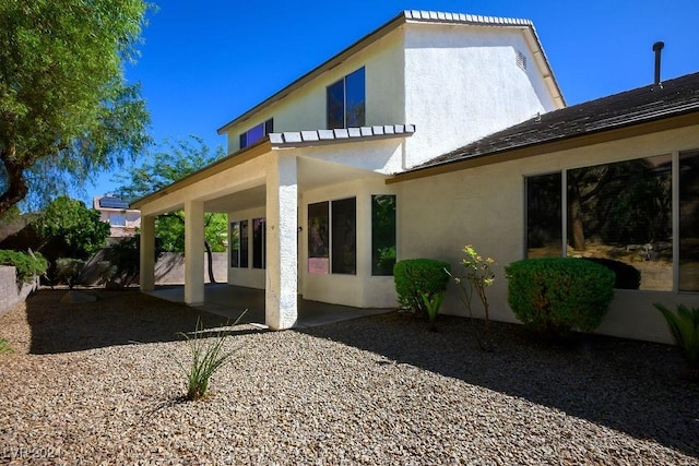 rear view of house with a patio area and stucco siding