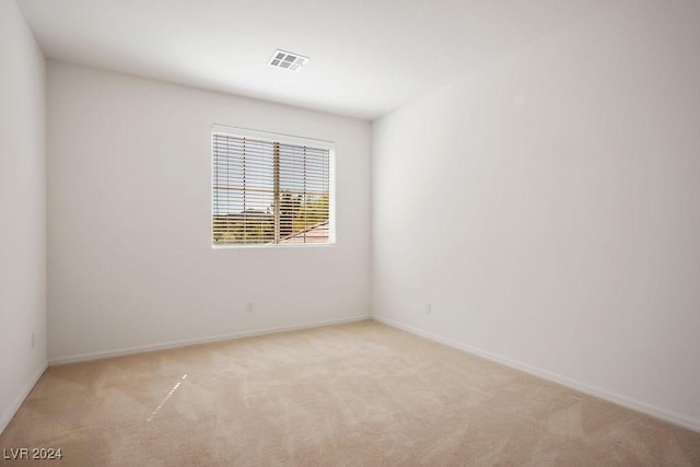 spare room featuring light carpet, baseboards, and visible vents