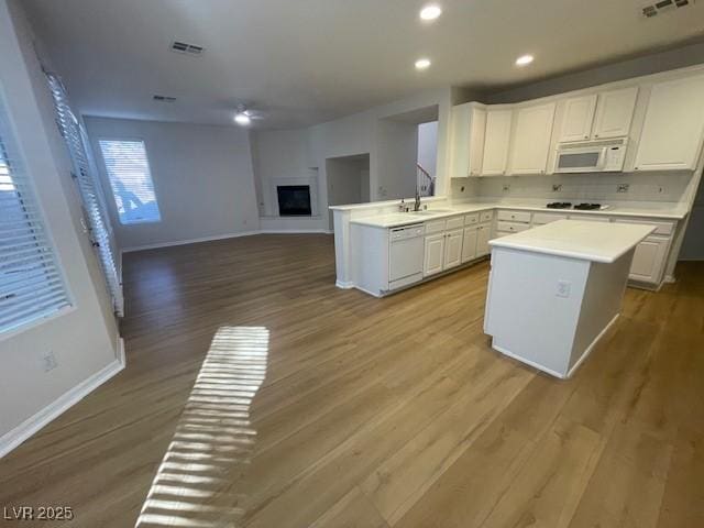 kitchen featuring light countertops, open floor plan, white cabinetry, white appliances, and a peninsula