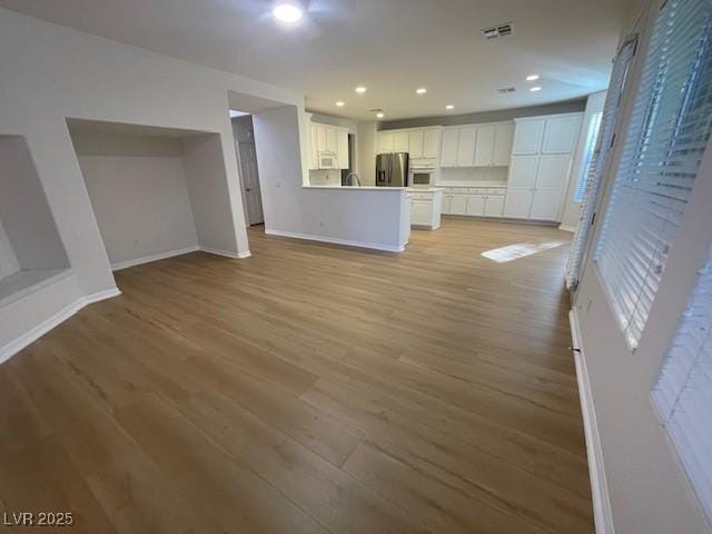 unfurnished living room with light wood-style floors, recessed lighting, visible vents, and baseboards