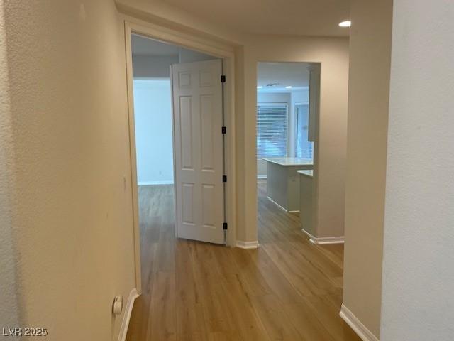 hallway with light wood-style floors and baseboards