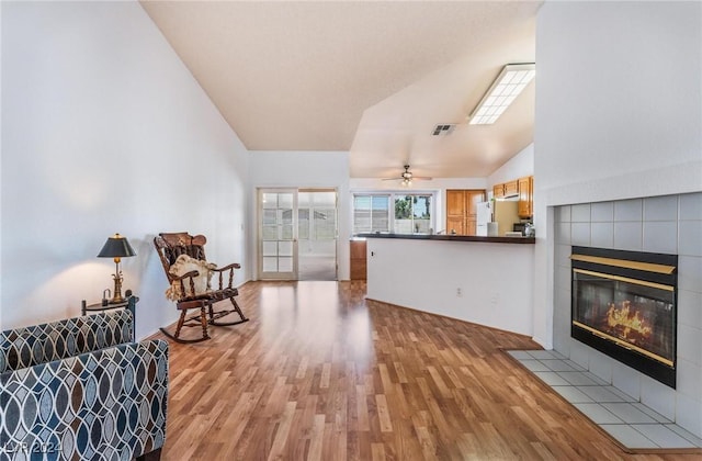 sitting room featuring high vaulted ceiling, a fireplace, and light hardwood / wood-style floors