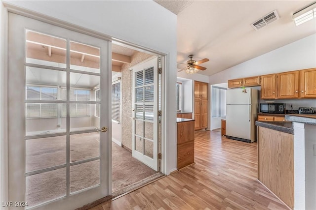 kitchen featuring vaulted ceiling, white fridge, ceiling fan, light hardwood / wood-style floors, and french doors